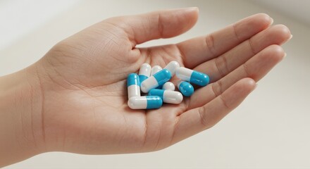Hand holding capsules and pills against a light background  