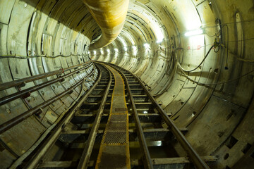 Underground tunnel infrastructure. Transport pipeline by Tunnel Boring Machine for electric train subway  with engineer or technician control and ventilation pipe.