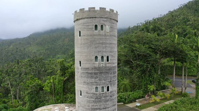 Pull-back drone shot of the Yokahu Tower in El Yunque National Forest, Puerto Rico, on a cloudy day