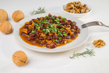 Red beans in tomato sauce with green onions and walnuts. Lenten vegetarian food