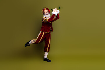 Elderly man dressed as a Renaissance nobleman holding a flute on khaki background © deagreez