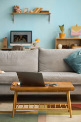 Modern living room with laptop on table, bookshelf and digital devices in background along with colorful decor, creating an inviting workspace