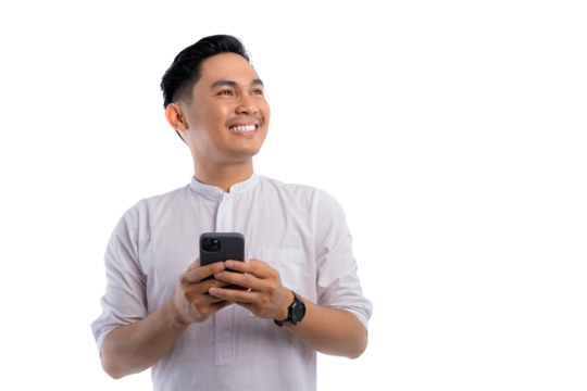 Happy Asian Muslim man holding smartphone, looking aside at free space, thinking about online offer isolated on transparent background