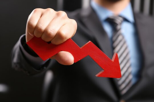 A Man Holds Red Arrow Pointing Downward Showing Economic Decline or Loss