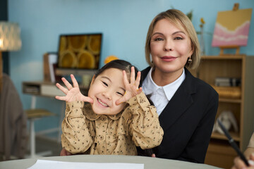 Portrait of young child smiling brightly and senior caregiver sitting together in cozy room