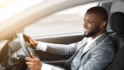 Cheerful african american businessman driving to work, shot through window, side view