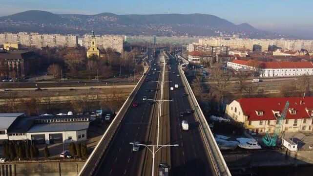 Flyover of urban traffic paths in Budapest converging at bridge with warm evening tones