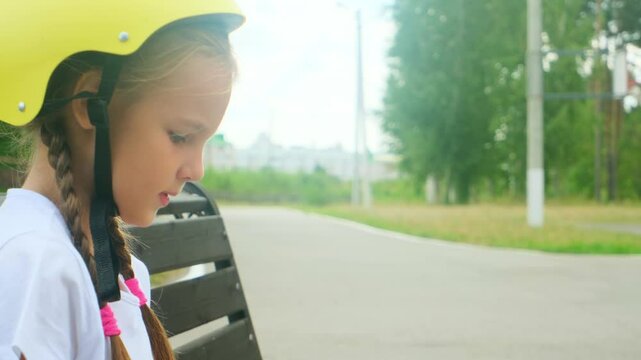 Young skater girl putting on protective shin guards and knee pads for skating. child rollerblader preparing for a ride in skatepark in summer