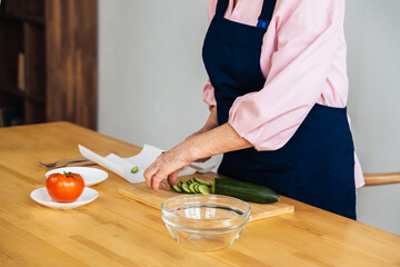 beautiful senior woman making healthy salad at kitchen. Family Meal Time.