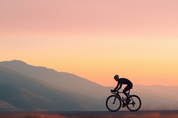 Obraz premium Silhouette of cyclist at sunrise against mountain landscape