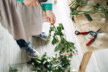 Person trimming flower stems with garden shears while holding a bouquet of pink roses. Floral care routine, sustainable floristry, handmade bouquets, behind the bloom