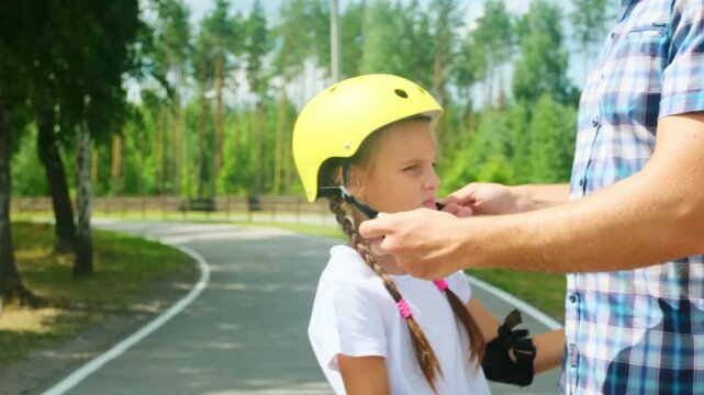Father helped her daughter wear a yellow helmet while enjoying time together in the park