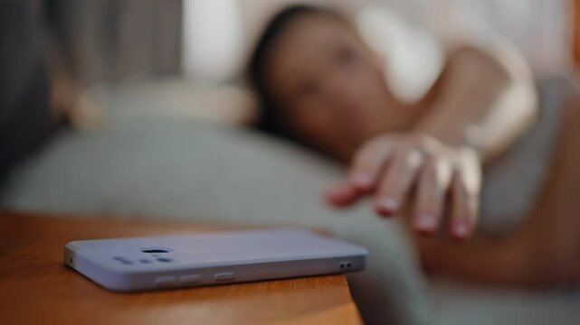 Sleepy girl reaching smartphone lying in cozy home bed closeup. Beautiful woman
