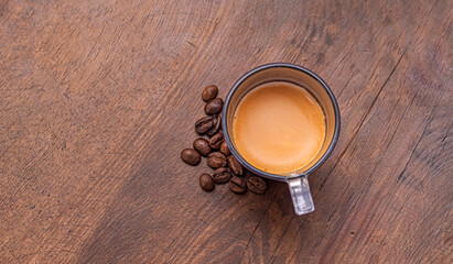 Scattered coffee beans with espresso served in a glass mug. The creamy crema on top of the espresso adds visual appeal. Perfect for coffee-related branding and blogs.