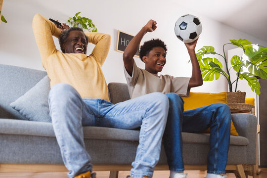 Happy senior man and grandson enjoying match together at home