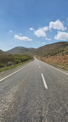 an asphalt road marked with white lines against cloudy blue sky
