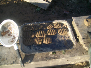 Homemade traditional cookies drying on a tray in an outdoor kitchen setup during a sunny afternoon