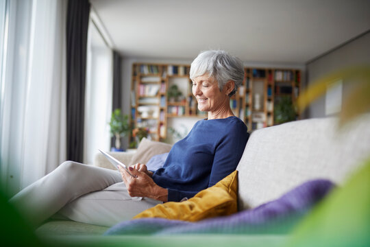 Senior woman using a tablet at home in a cozy living room