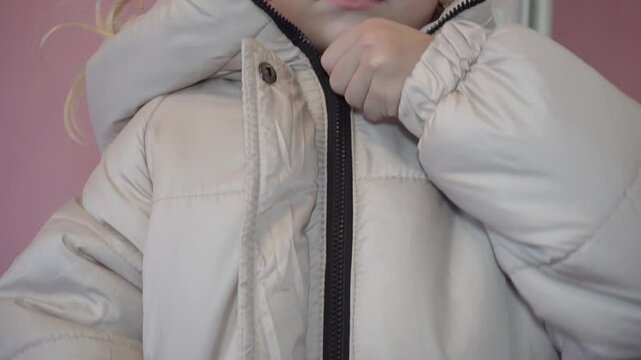 fastening a zipper on a jacket, the girl put on a jacket and fastened the zipper with her hand