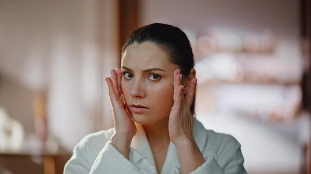 Worried woman touching face looking home mirror in robe closeup. Concerned lady