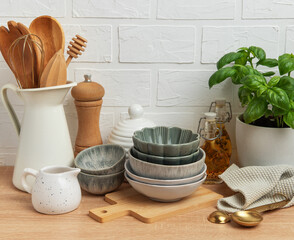 Kitchen utensils, bowls and spices resting on wooden countertop with white brick wall background