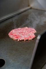 Gros plan sur un steak juteux en pleine cuisson sur une plancha professionnelle, révélant sa texture savoureuse.