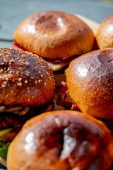 Vue sur plusieurs hamburgers faits maison avec des steaks, de la salade, du fromage fondant, le tout disposé sur une planche en bois.