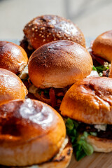 Vue sur plusieurs hamburgers faits maison avec des steaks, de la salade, du fromage fondant, le tout disposé sur une planche en bois.
