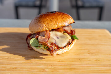 Gros plan sur un hamburger fait maison avec du fromage fondant, un steak, du bacon et de la salade,...