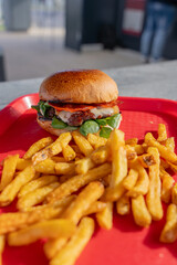 Hamburgers faits maison accompagnés de frites croustillantes, joliment présentés sur un plateau rouge dans un restaurant spécialisé.