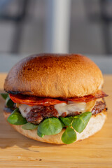 Gros plan sur un hamburger fait maison garni de chorizo épicé et de fromage fondant, dans un cadre de restauration.