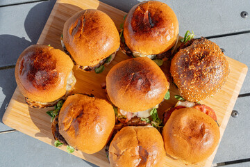 Vue de plusieurs hamburgers faits maison servis sur une planche en bambou dans un restaurant spécialisé.