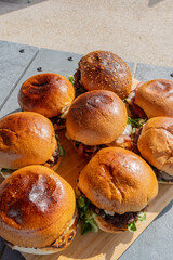 Vue de plusieurs hamburgers faits maison servis sur une planche en bambou dans un restaurant spécialisé.