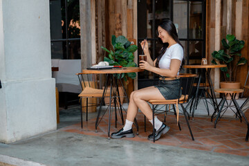Young woman enjoying iced coffee at outdoor cafe, stirring with straw