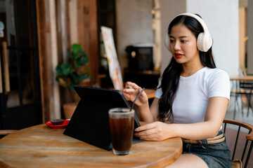 Freelancer working remotely at cafe using tablet and headphones