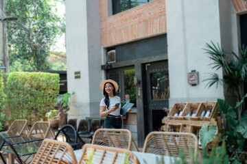 Asian restaurant manager walking in the dehor holding a tablet and a smartphone