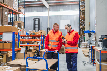 Two warehouse workers are scanning packages with a barcode scanner in a large distribution center
