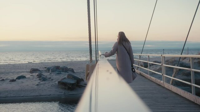 Woman Walking on Bridge Over Water at Sunset