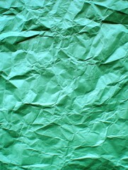 Vivid crumpled green paper texture background showcasing intricate folds and shadows creating a compelling abstract pattern perfect for graphic design