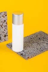 Cosmetic product in tube, bottle, lotion or serum with stylish props on yellow background. 