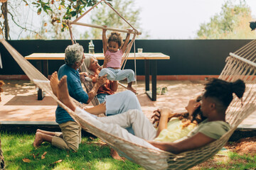 Multi-ethnic family relaxing together in garden hammocks