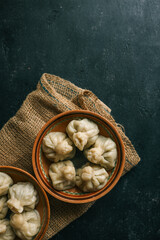 Two clay bowls filled with traditional dumplings placed on a rustic burlap cloth over a dark...