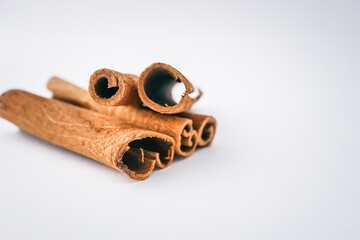 Cinnamon sticks arranged on a white background in soft natural light, showcasing texture and spice...