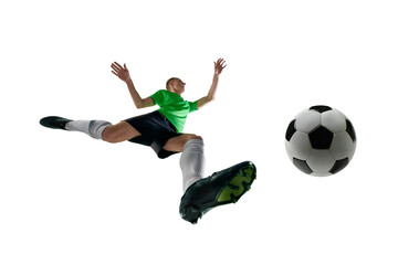 Naklejka premium Low angle of male athlete, dressed sport uniform, soccer player leaping to kick ball in motion against white studio background. Concept of professional sport, training, tournament, energy. Ad