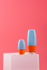Plastic blue tube for cream or lotion. Skin care or sunscreen cosmetic with stylish props on pink background.