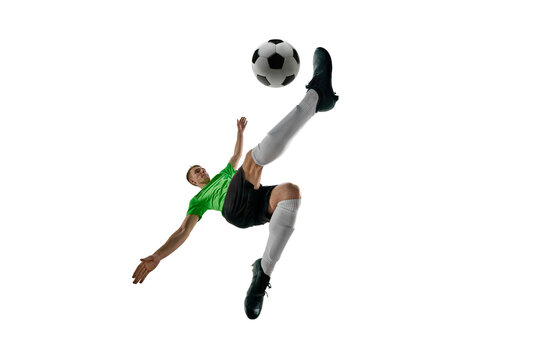 Low angle of strong man, dressed sport uniform, soccer player leaping for bicycle kick against white studio background. Concept of professional sport, training, tournament, energy. Ad