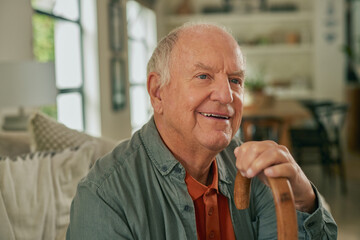 Happy senior man holding wooden stick at home