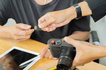  Photographer give a memory card to stylists and  meeting in photography studio. Selective focus.