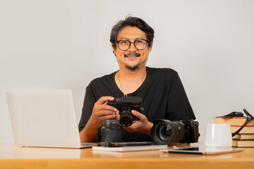 Protrait image of smiling adult handsome photographer with eyeglasses working with camera
