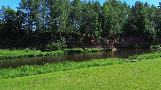 Low angle River flight with a drone next to red cliffs in Latvia